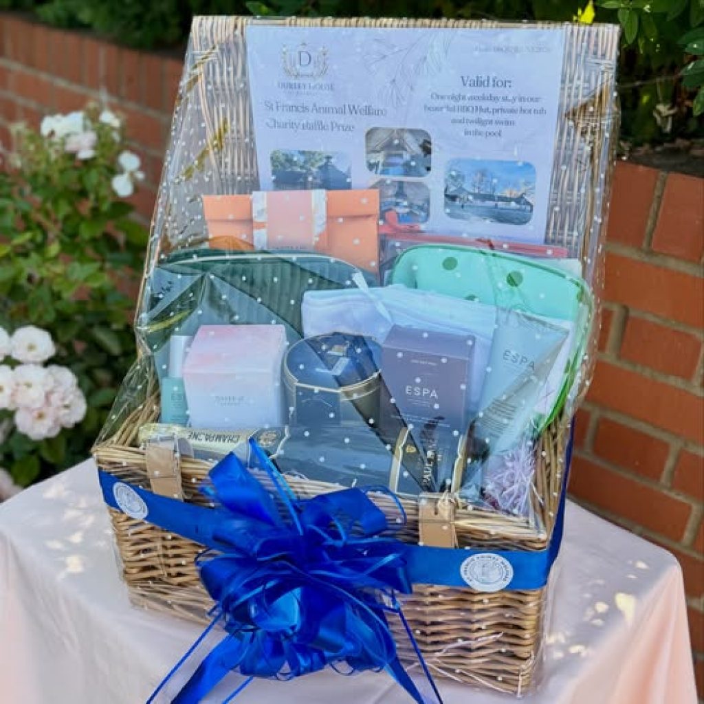 An Image of a hamper contain various prizes wrapped in a big blue bow